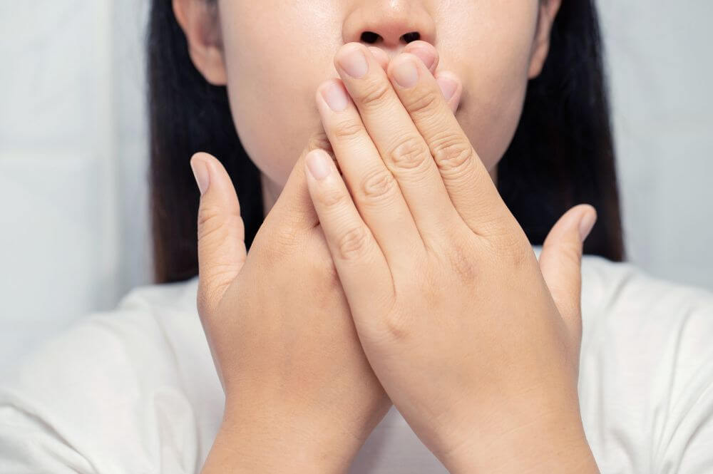 Girl covering her mouth due to bad breath